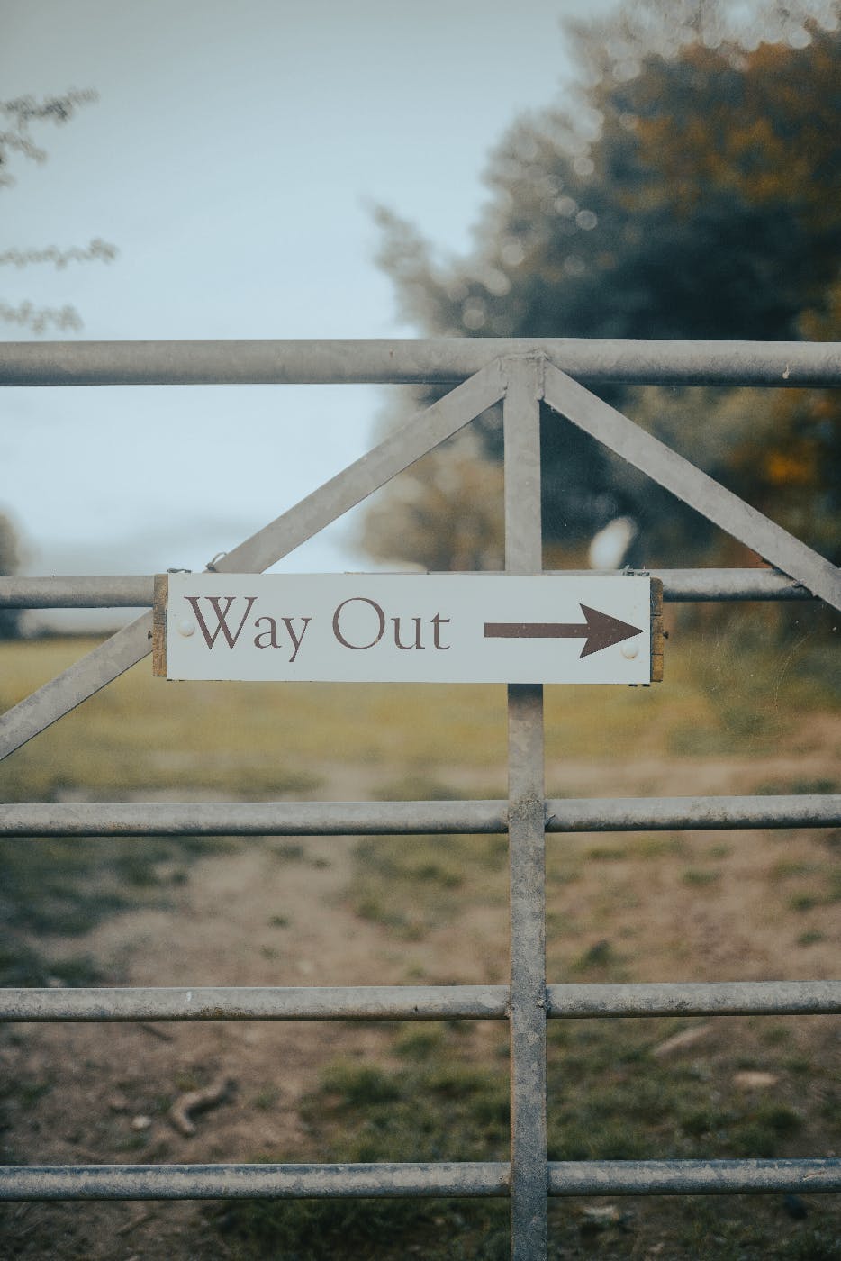 A gate on a dirt road with a sign reading Way Out and an arrow pointing right