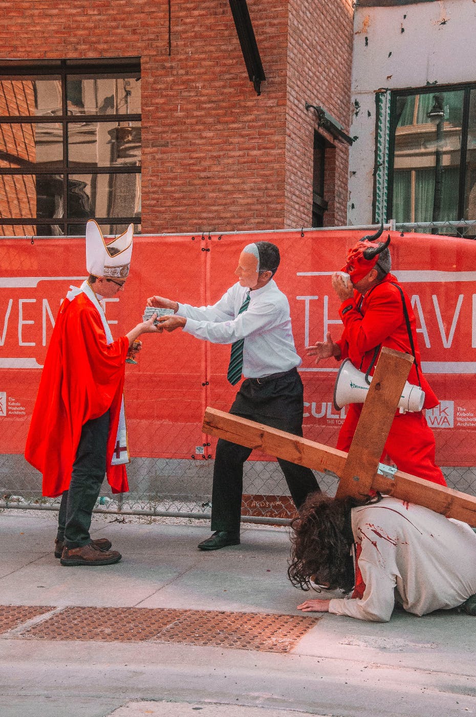 A street performance with a politician, a cardinal, the devil and a bloody man with a cross