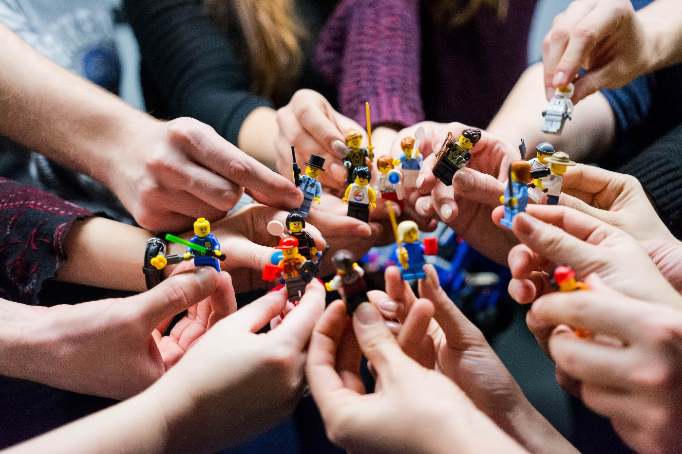 Peopl ein a cricle, just their hands, holdning Lego heroes.
