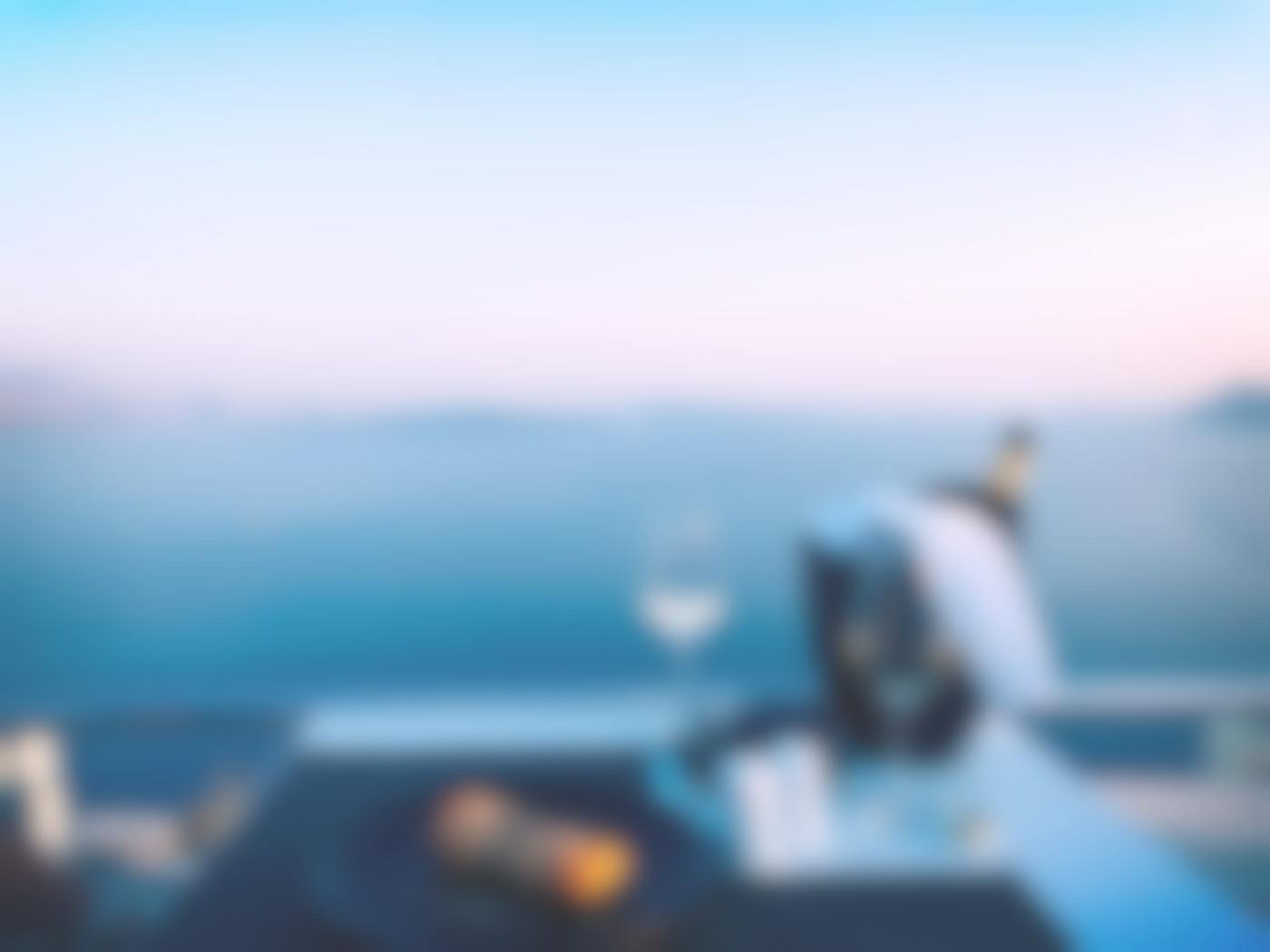 A table set for dinner, two wine glasses a bottle in wine bucket overlooking the ocean