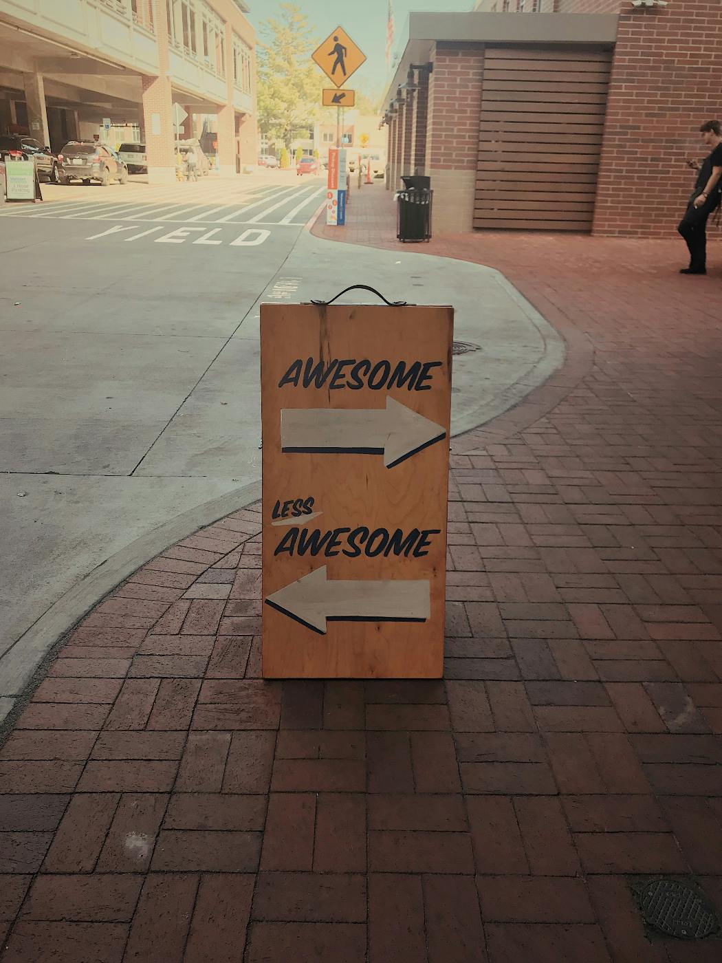 A street sign reading awesome with an arrow pointing right and less awesome with an arrow pointing left