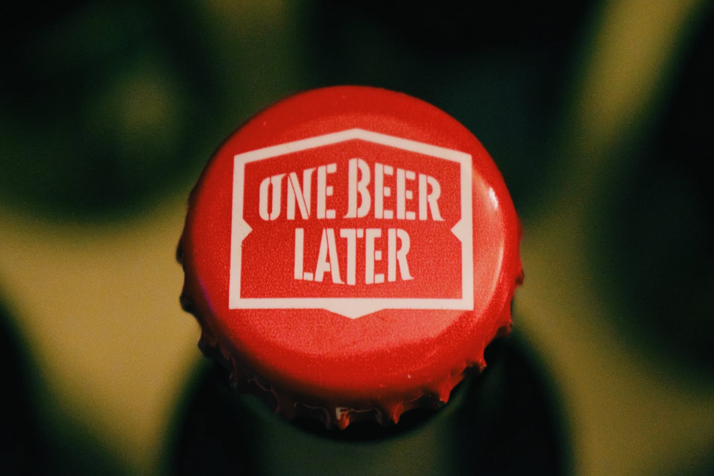 A red bottle cap with One Beer Later printed on it