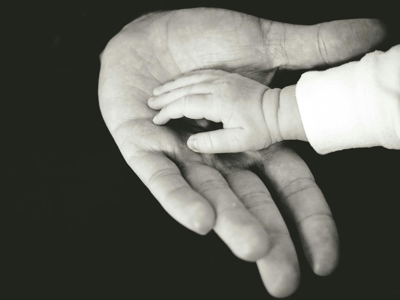 A child's hand resting in the palm of an adult's hand