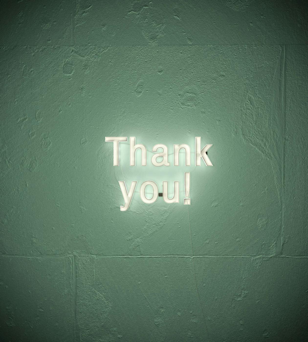 A green wall with a lighted sign reading Thank You