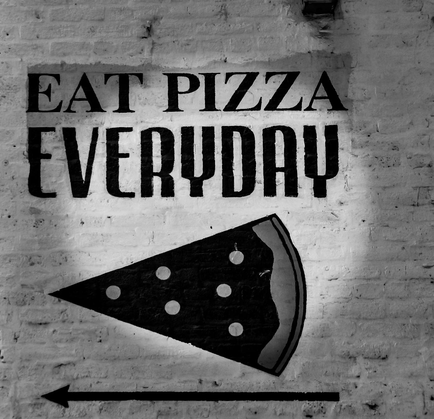 a white wall with the words Eat Pizza Everyday and a drawing of a pizza slice