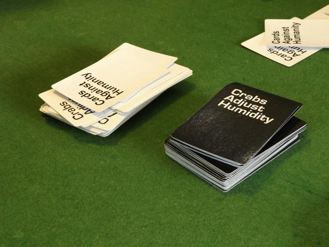Green table top with Cards Against Humanity cards in blakc and white