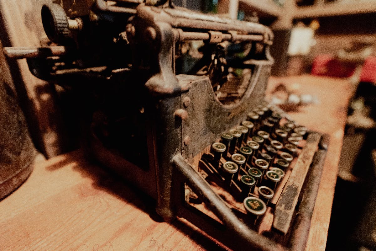 Old fashioned typwriter, rusted, dusty sitting on a work bench.