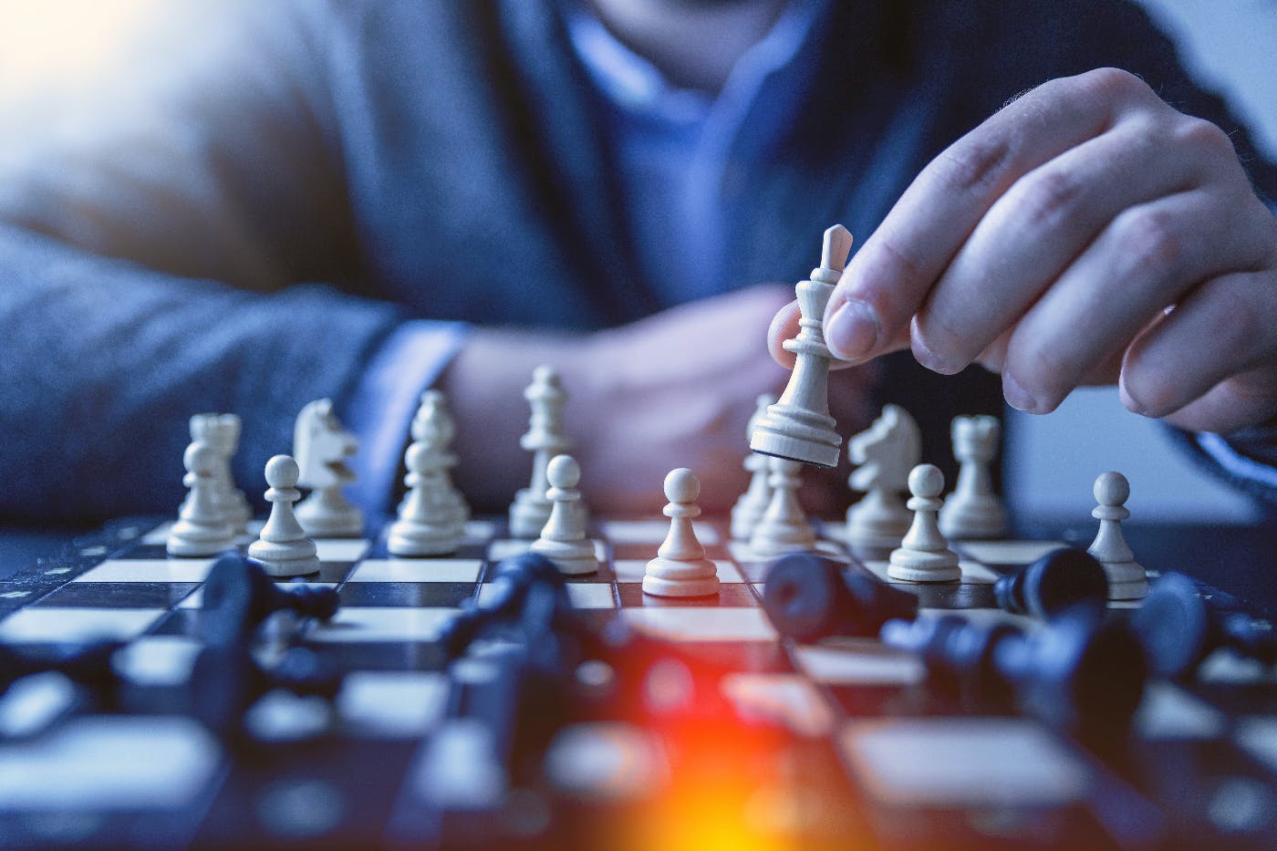 a  chess game, man holding his king above other toppled pieces