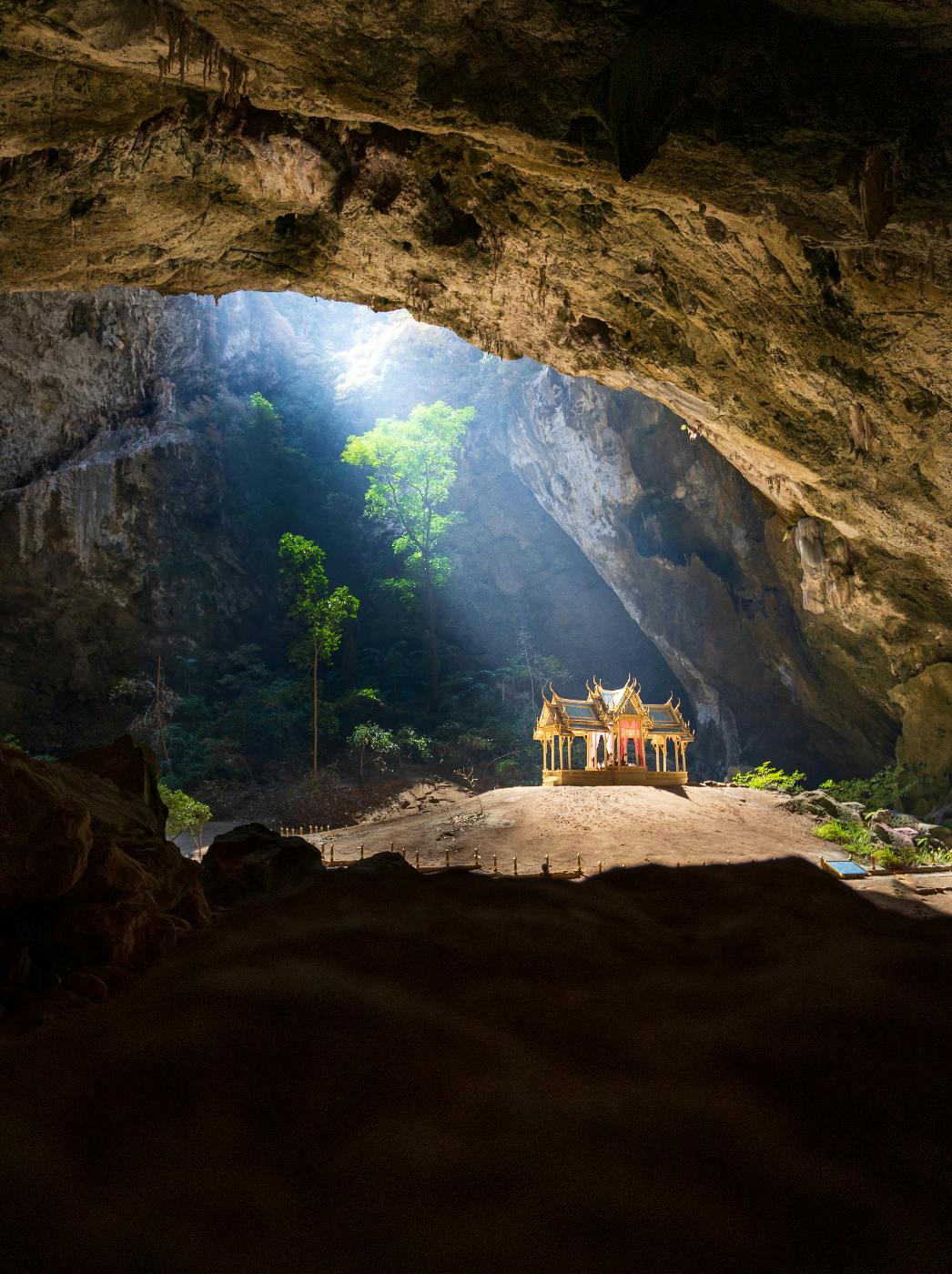 A small yellow pagoda in a deep, well-lit cave