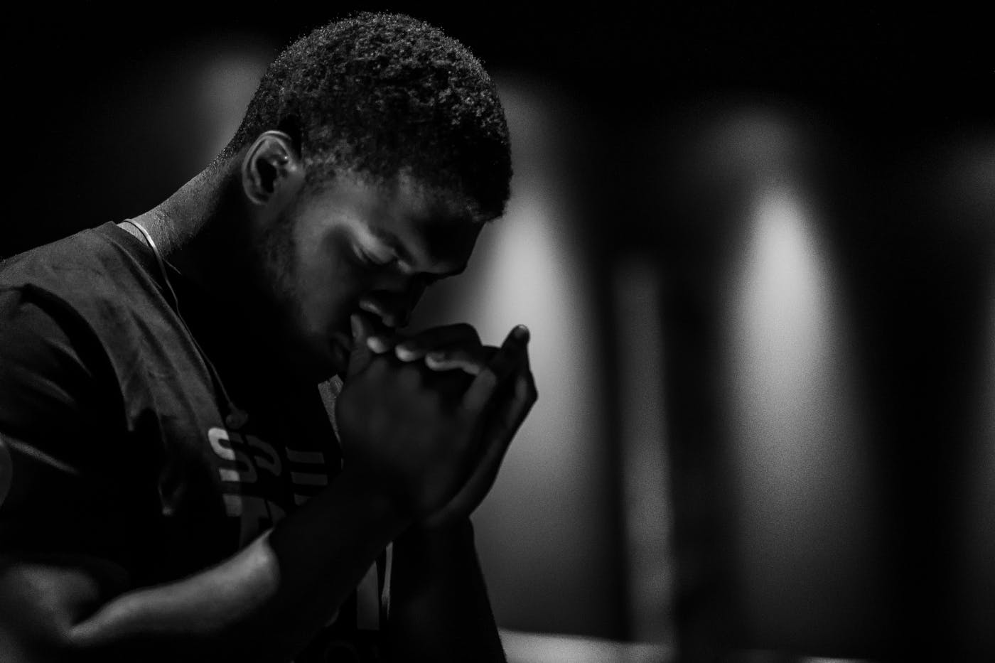 An African American man in deep, thoughtful prayer