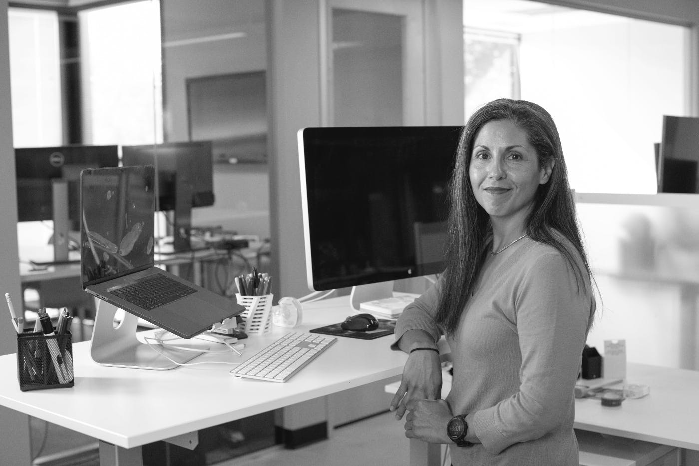 A female CEO standing at her desk with a computer screen