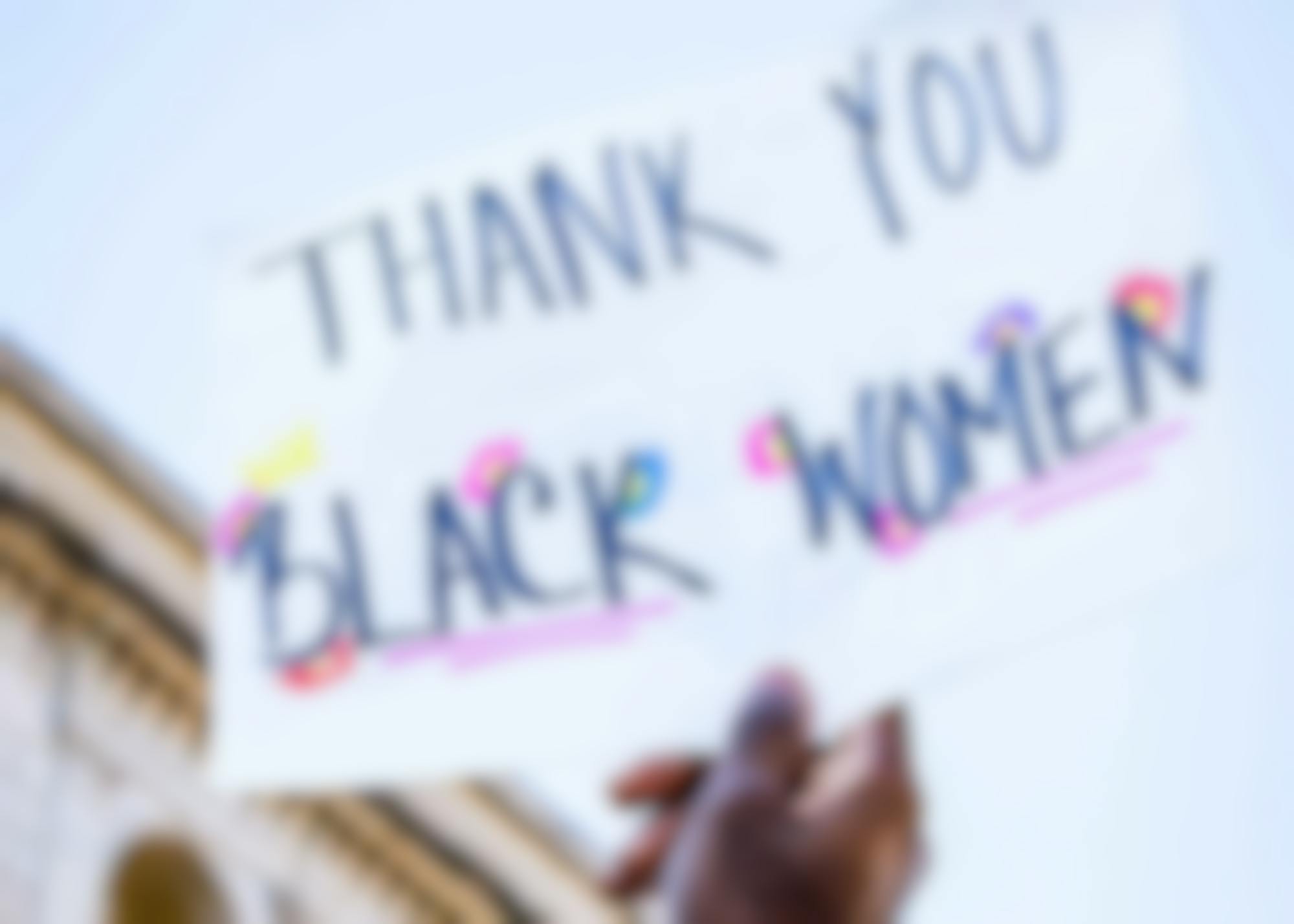 Woman holding a sign at a protest that reads "Thank you Black Women"