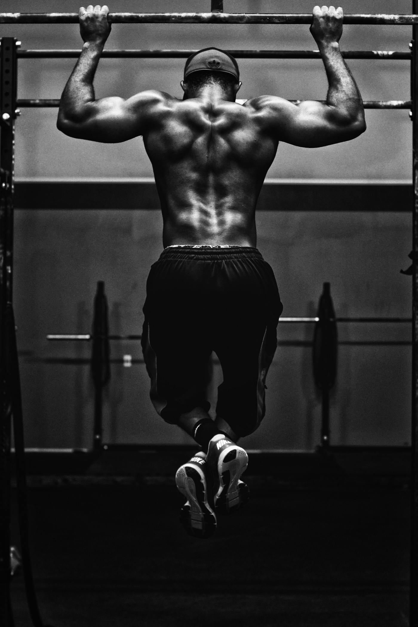 A muscular man on a pull up bar mid motion