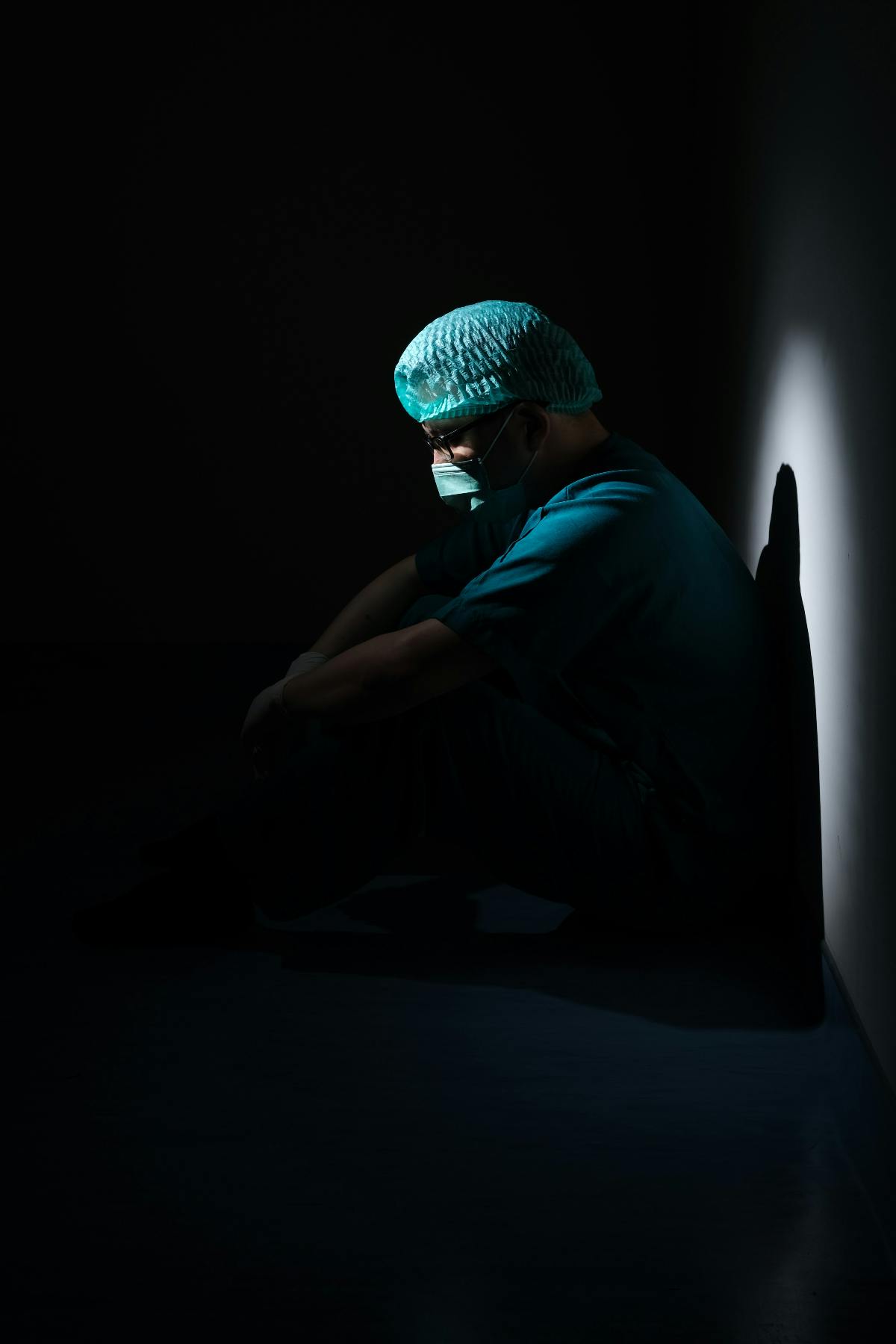 a doctor dressed for surgery sitting on the floor, preparing for the task at hand.