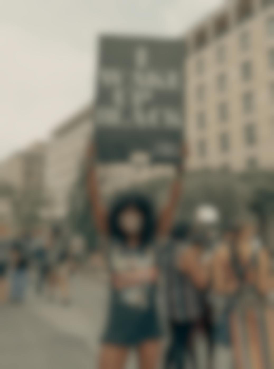 A young black woman at a protest holdning a sign t at reads, I Wake Up Black