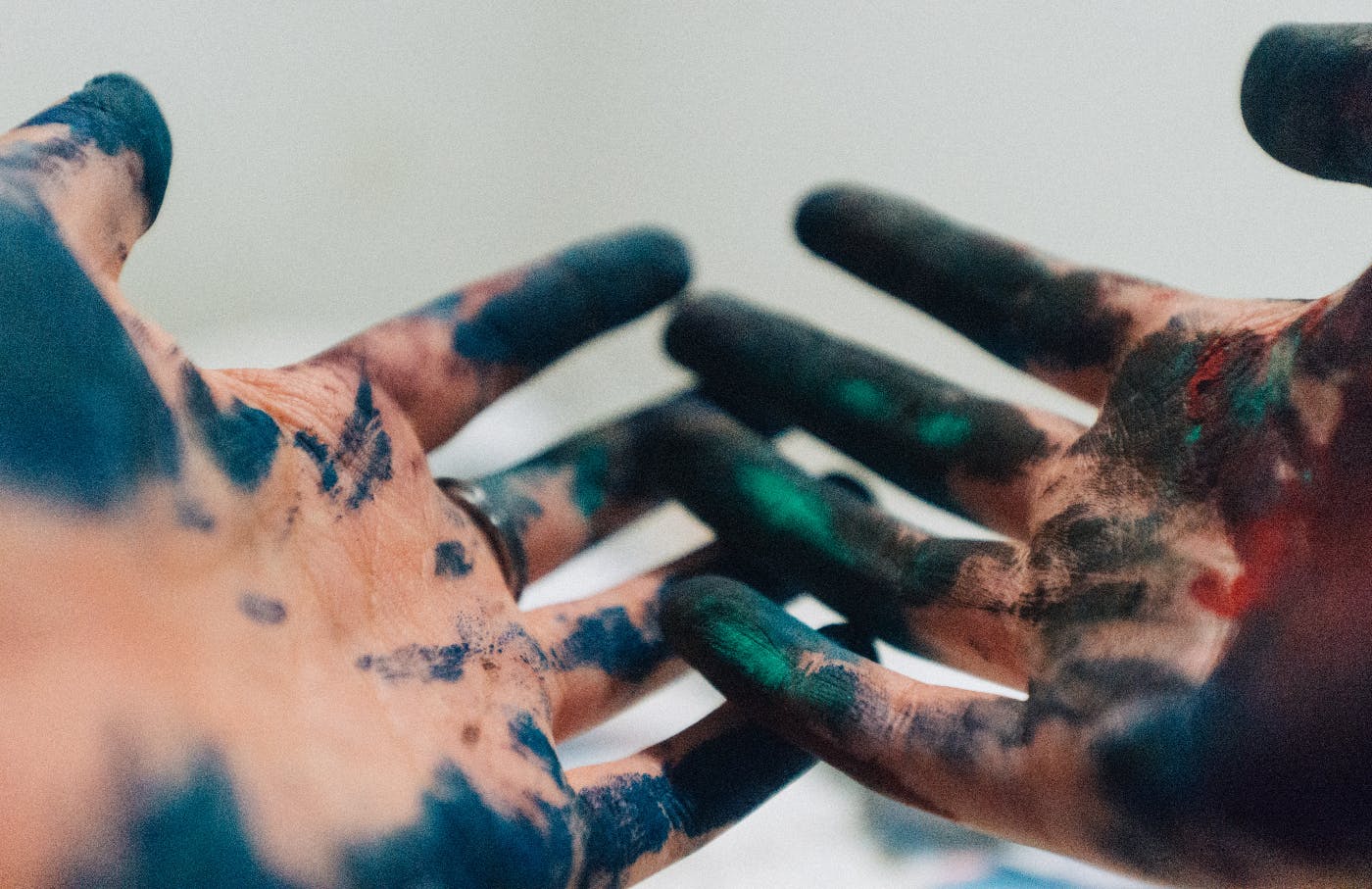 two hands covered with paint and charcoal