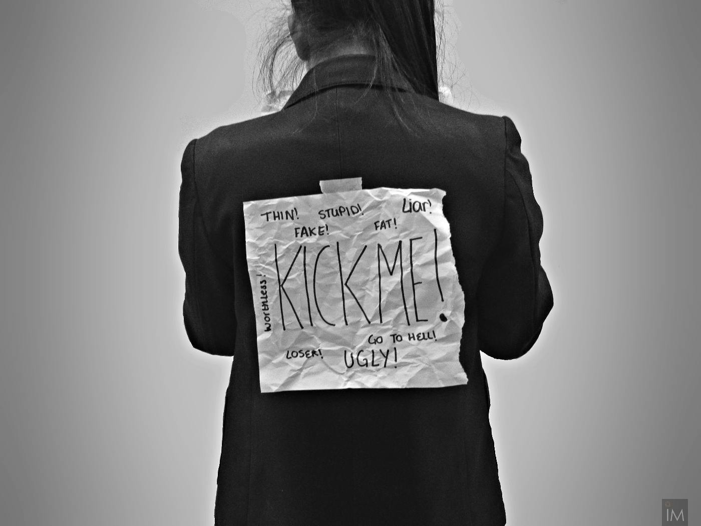 A girl with a sign on her back resding Kick Me! 