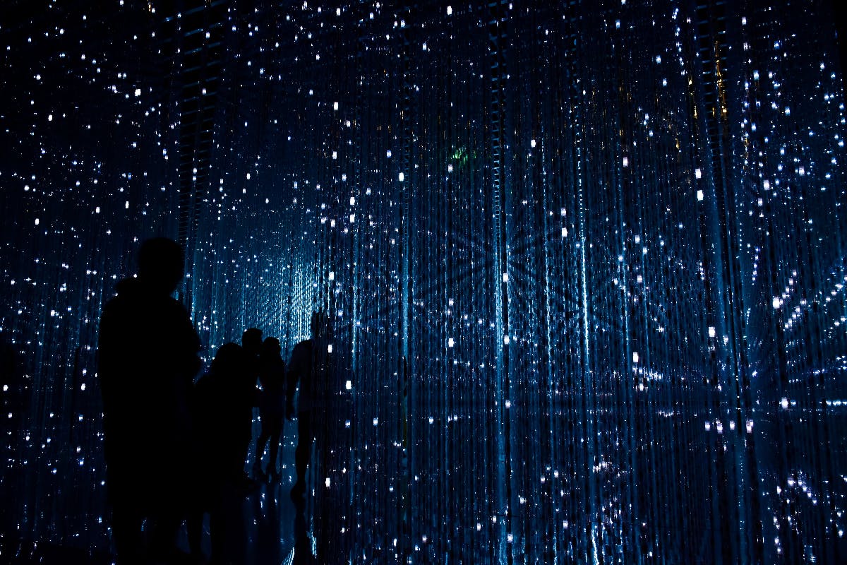 dark silhouettes of peopl ein a maze of blue techno lights.