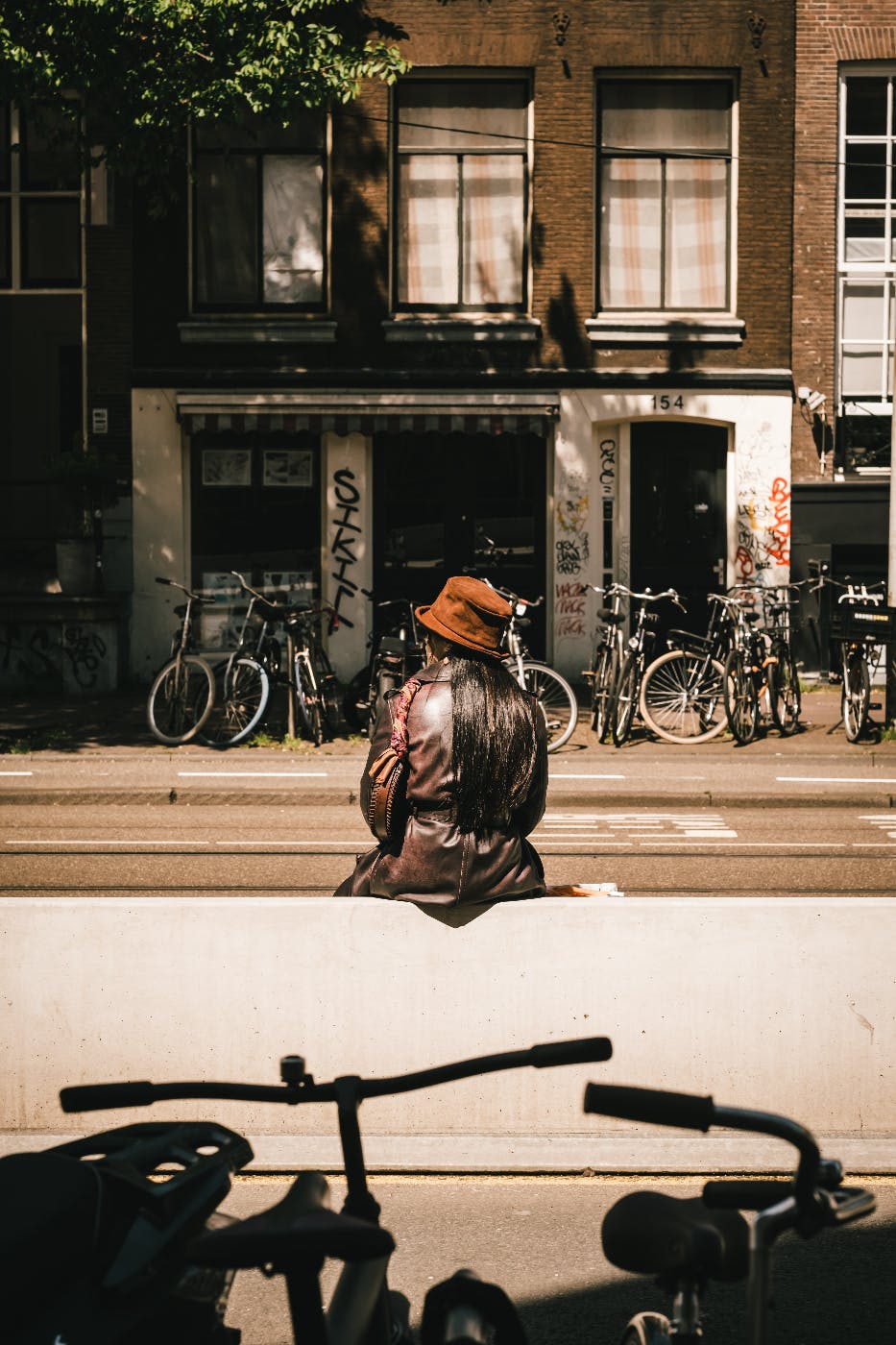 A woman sitting on a street divide sorrounded by bikes and the city