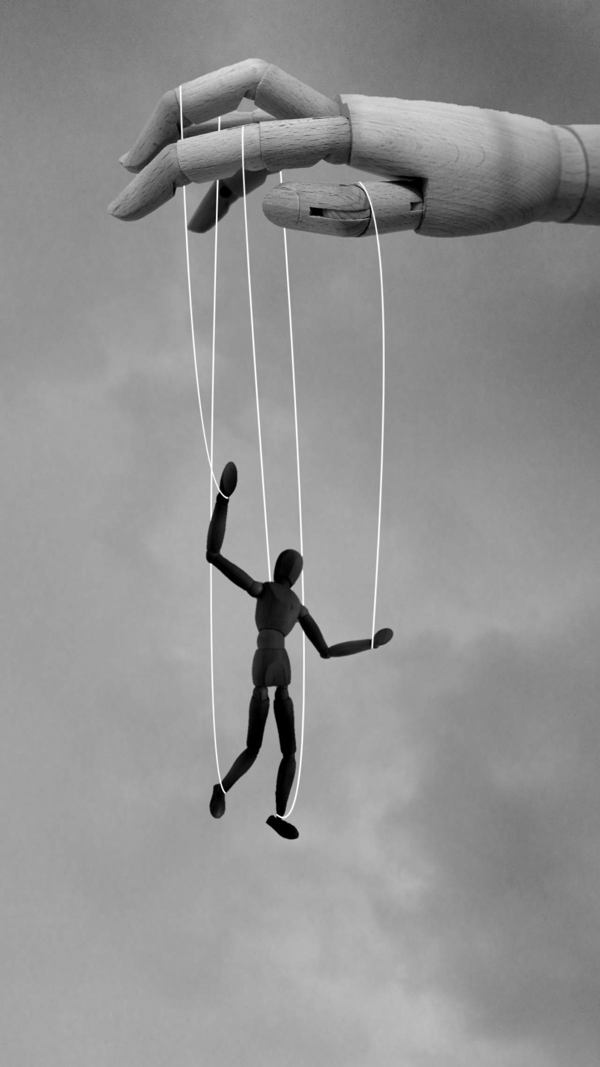 a wood hand manipulating a marionette puppet