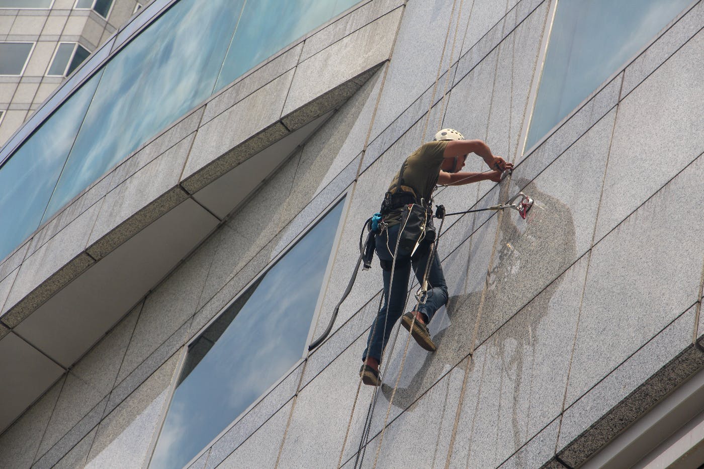A window washer harnessed to the side of a building