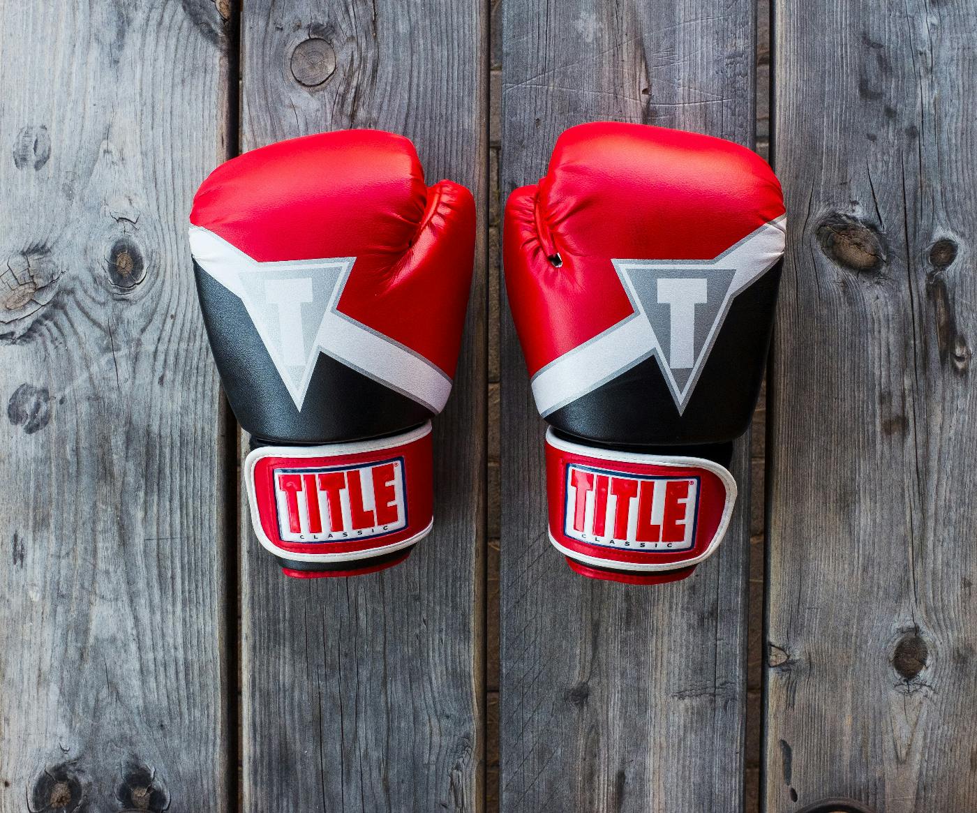 Two Title boxing gloves sitting on a wood slat table