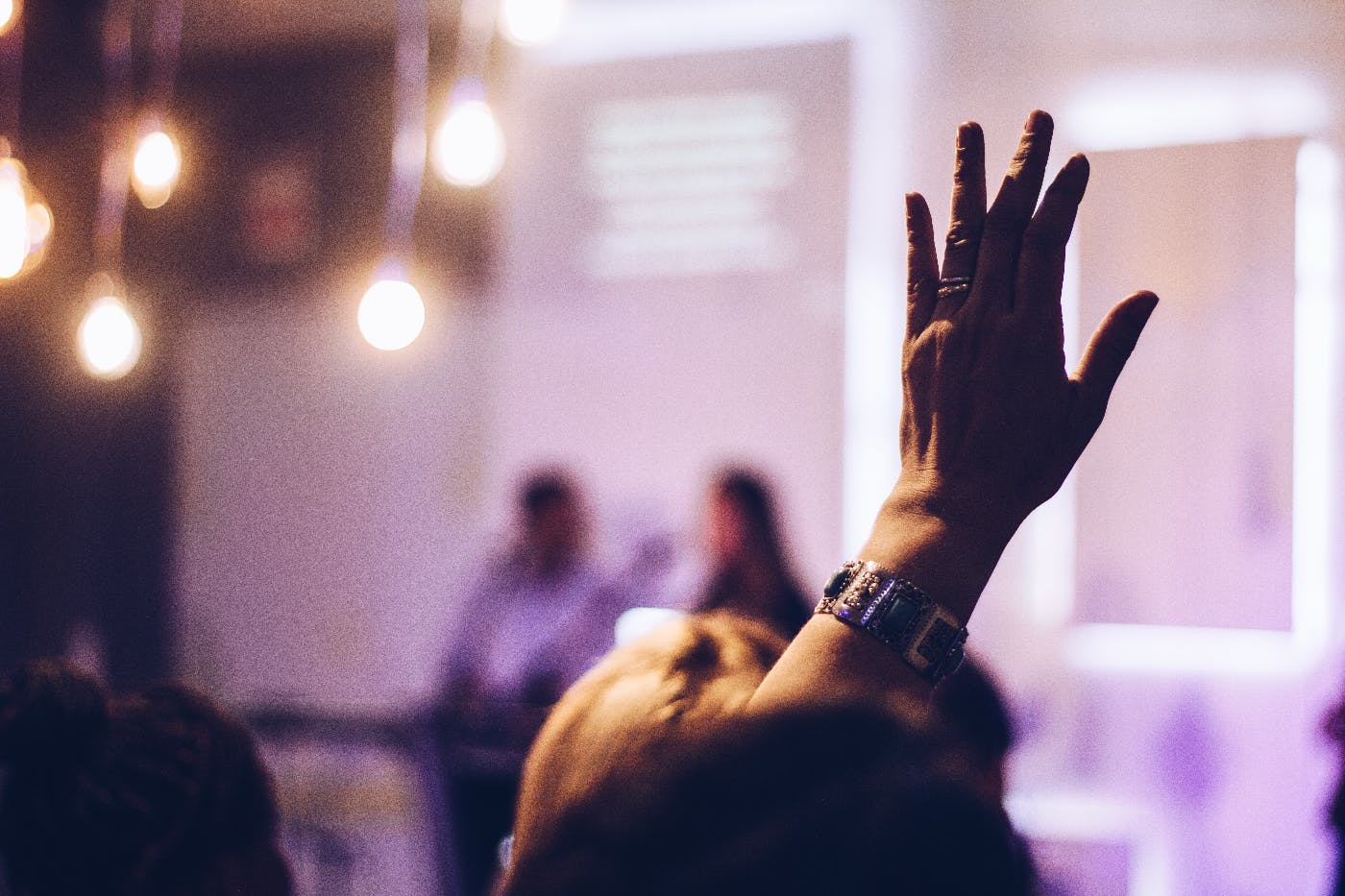 A raised hand in a lecture crowd