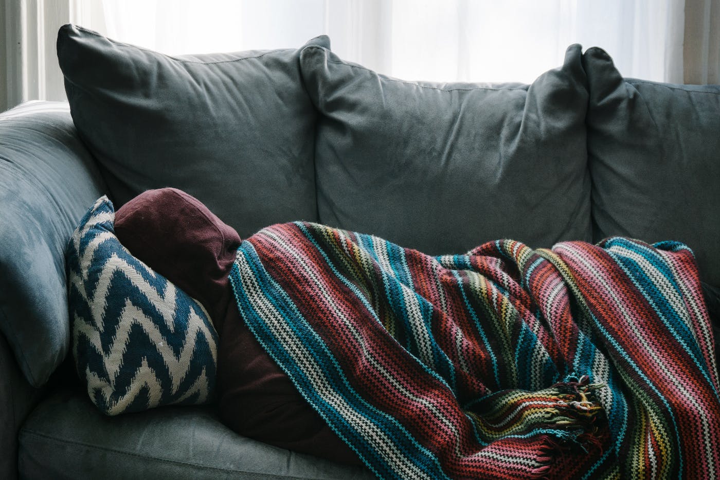 A person wrapped up and cozy on the couch