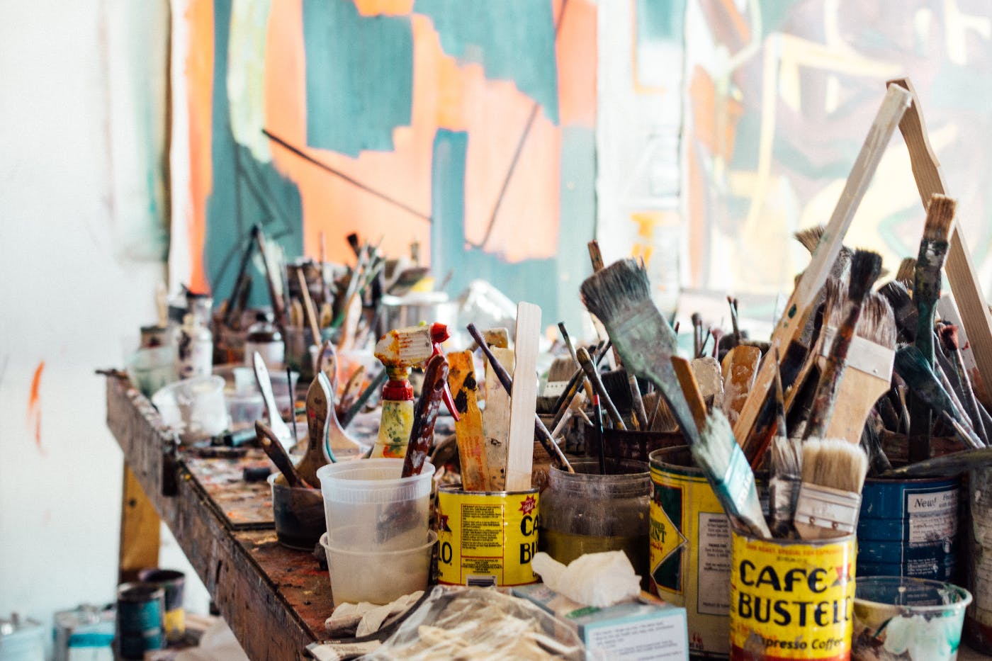 A painter's table covered with used brushes, cans, jars and paints
