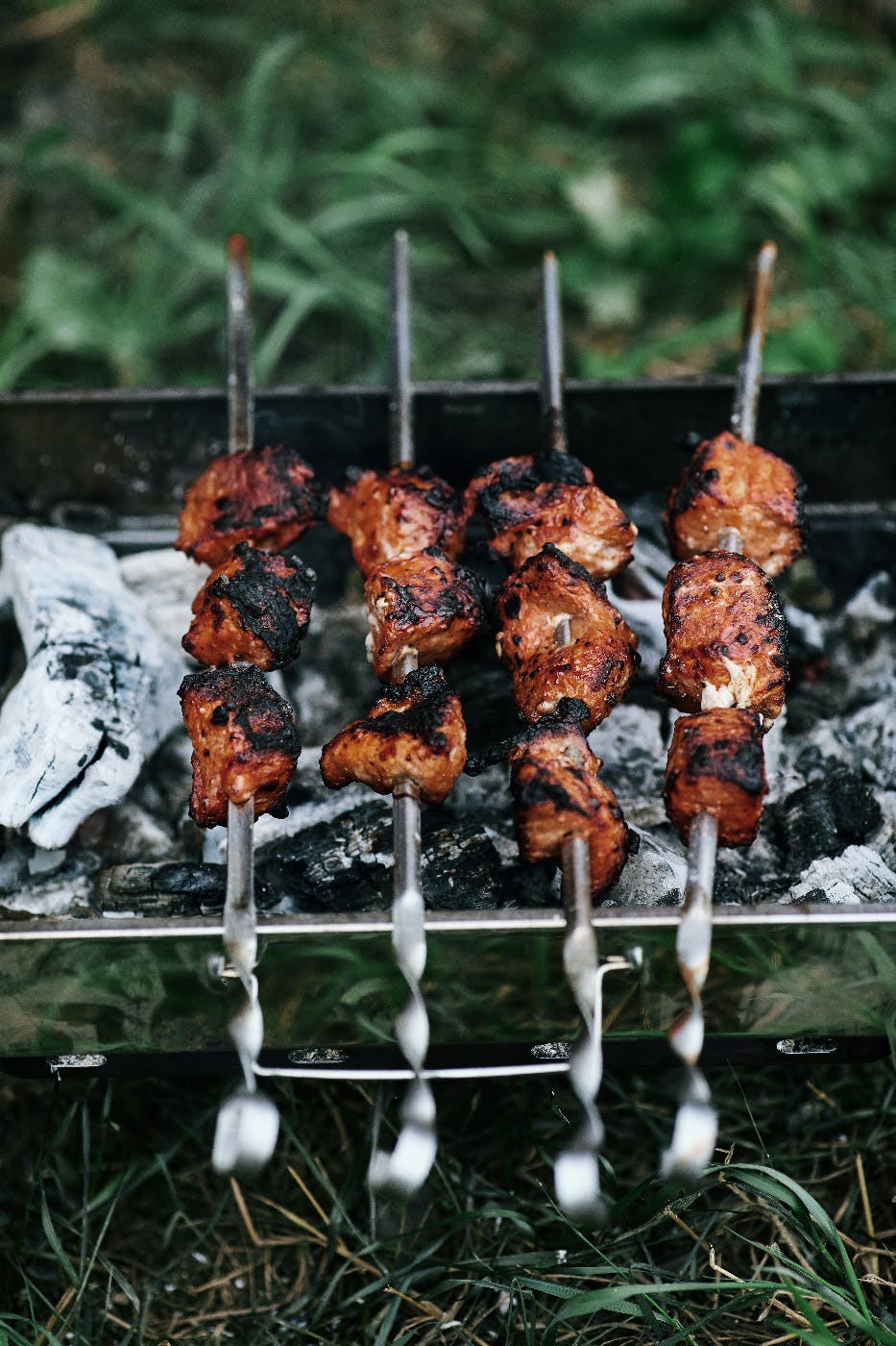 Chicken on metal skewers cooking over a wood fire