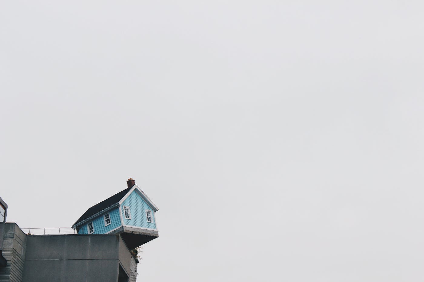 A blue house hanging over the end of a cliff