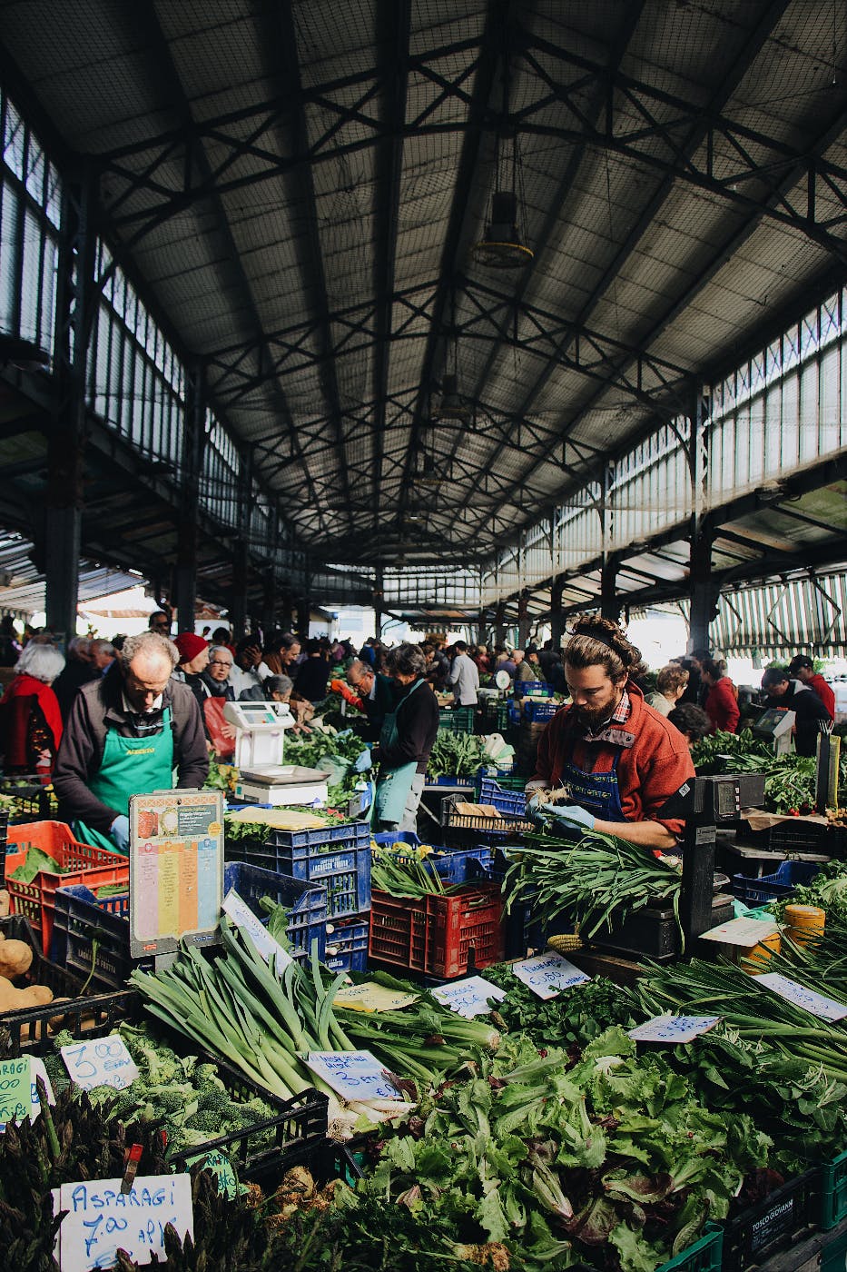 a crowded maketplace with vegetables in the foreground