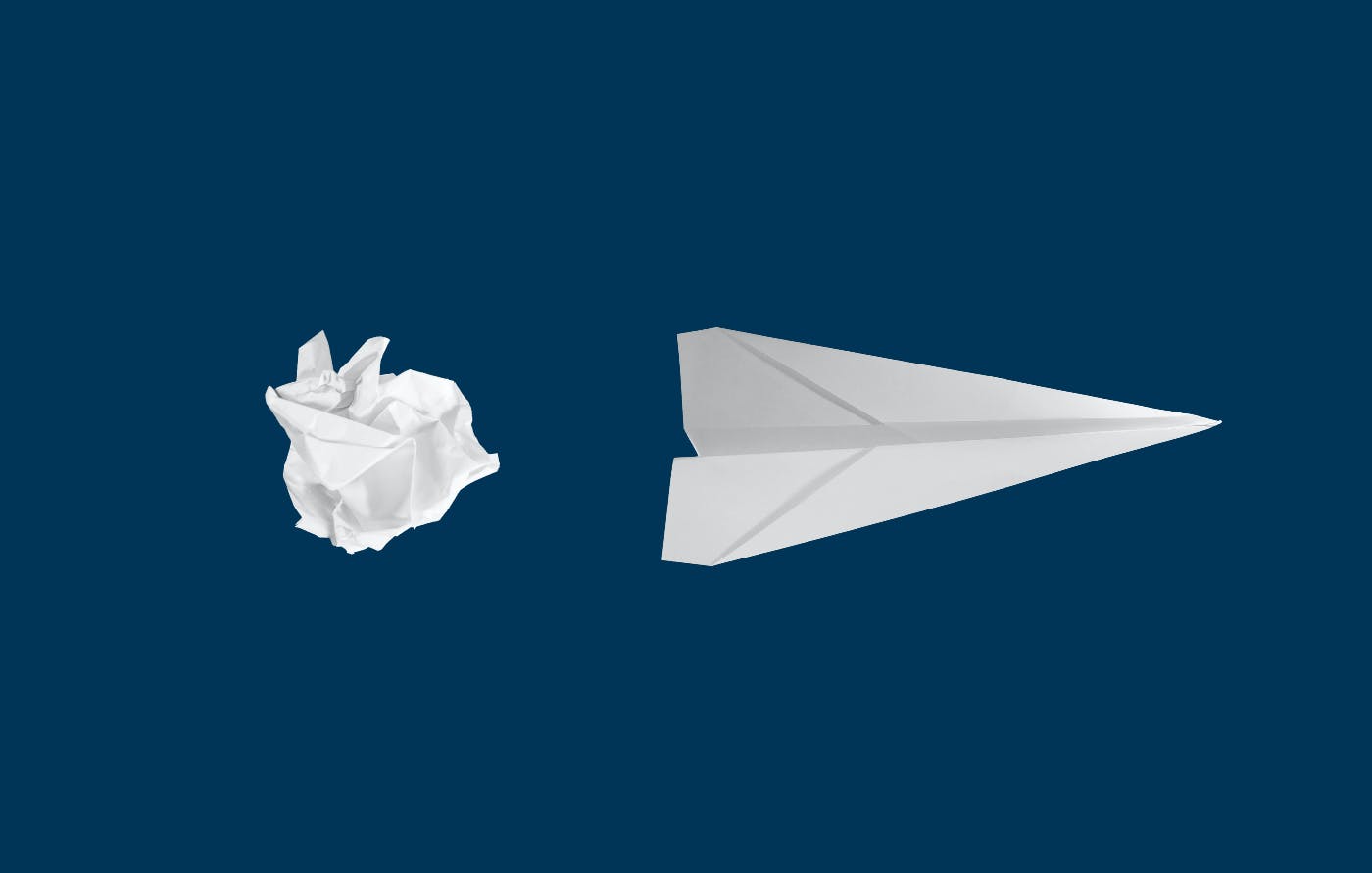a crumpled piece of white paper next to a white paper airplane on a blue background