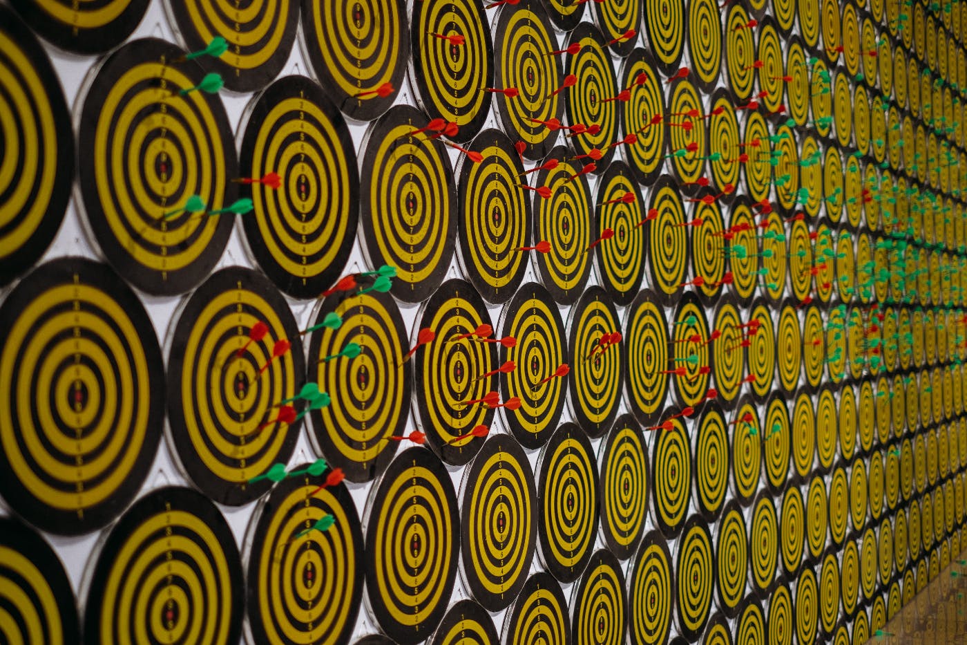 A wall with hundreds of dart boards with red and green darts in them