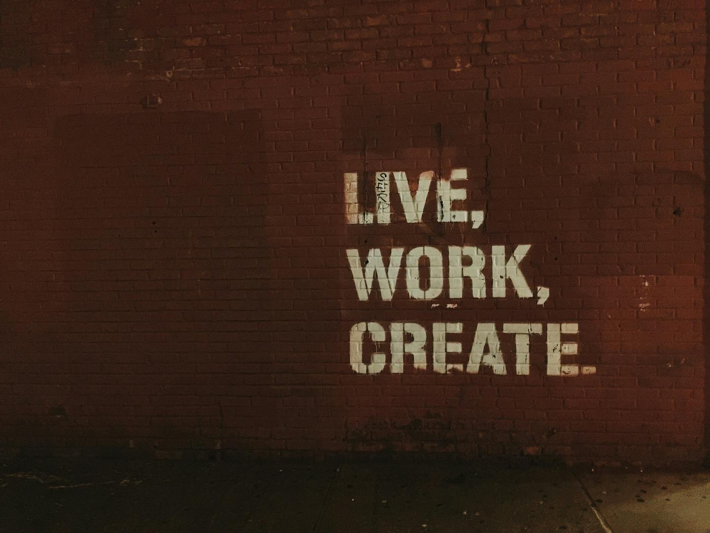 A brick wall with Live, Work, Create apinted on it.
