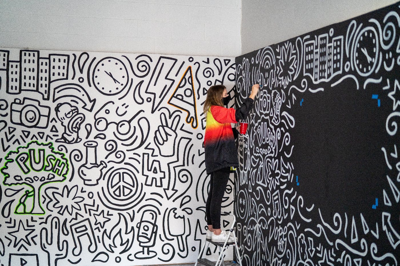 A woma drawing a mural on white and black walls