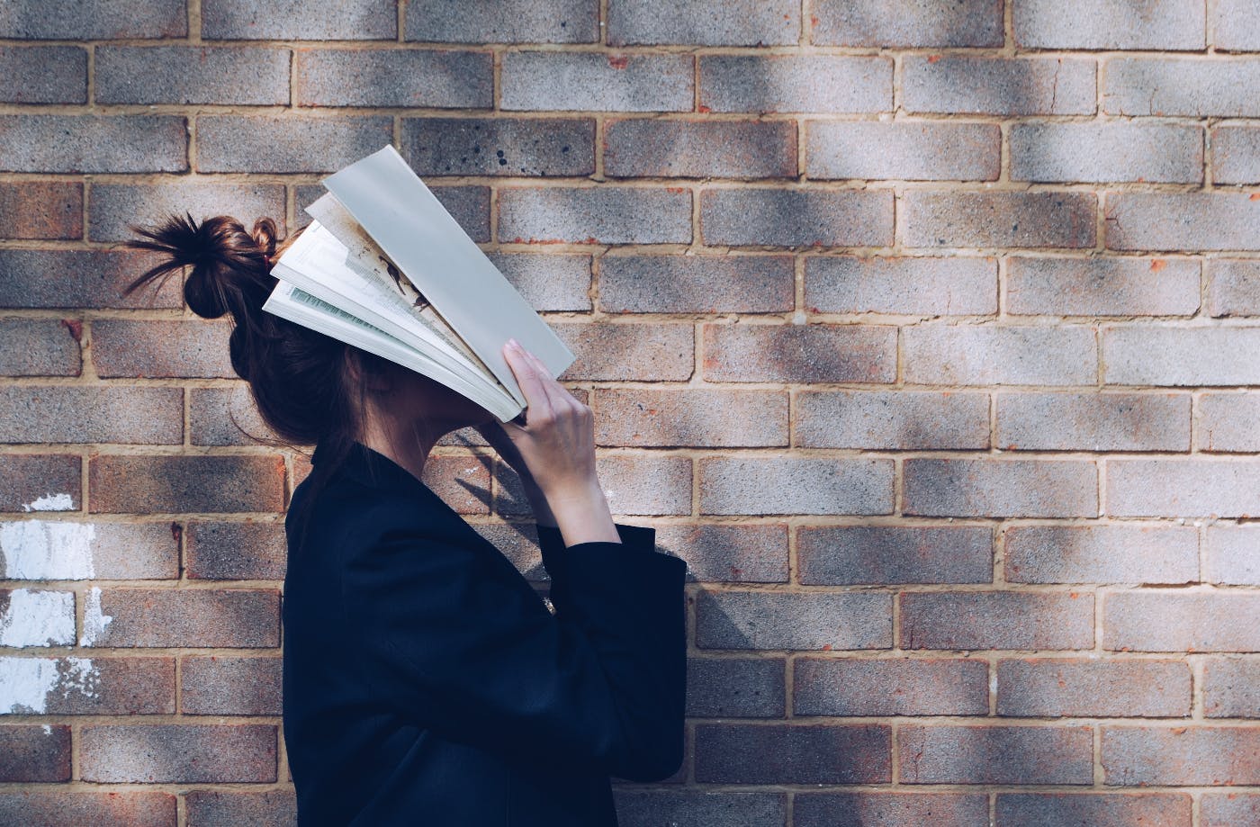 A girl covering her face with a book