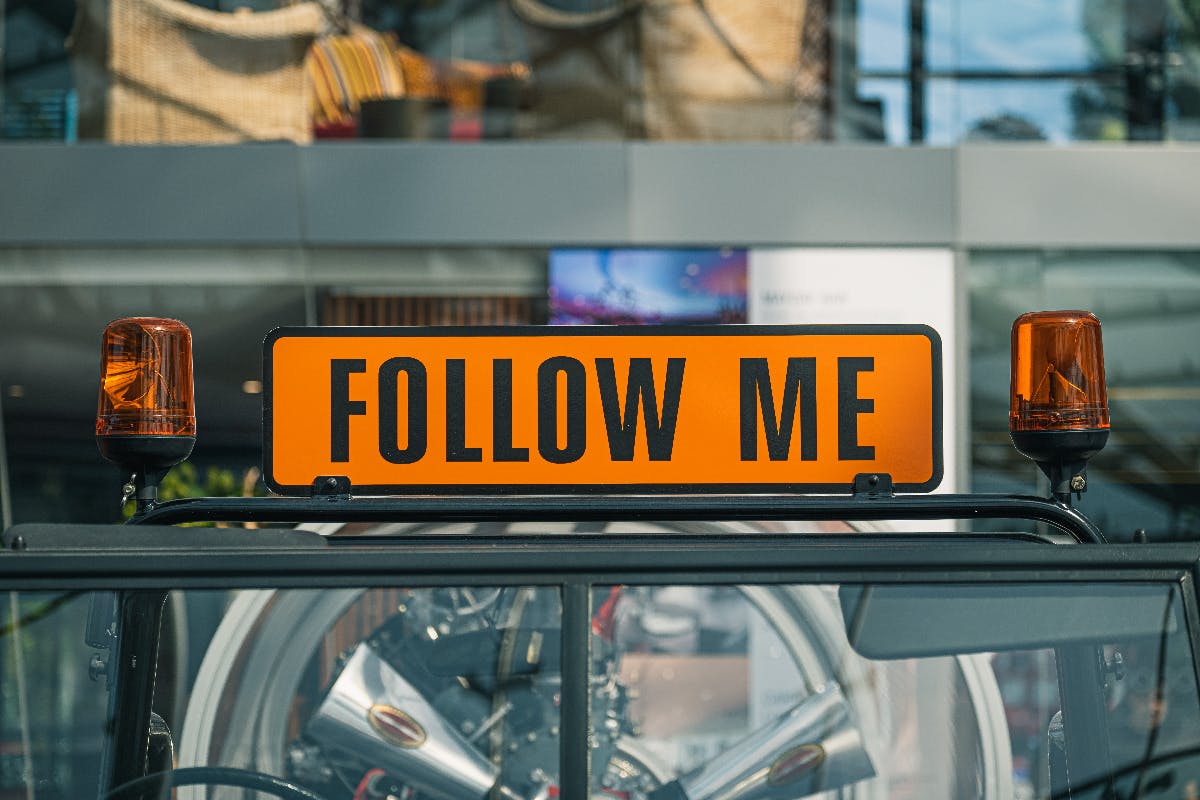 Image of a sign on the back of a truck reading "follow me."
