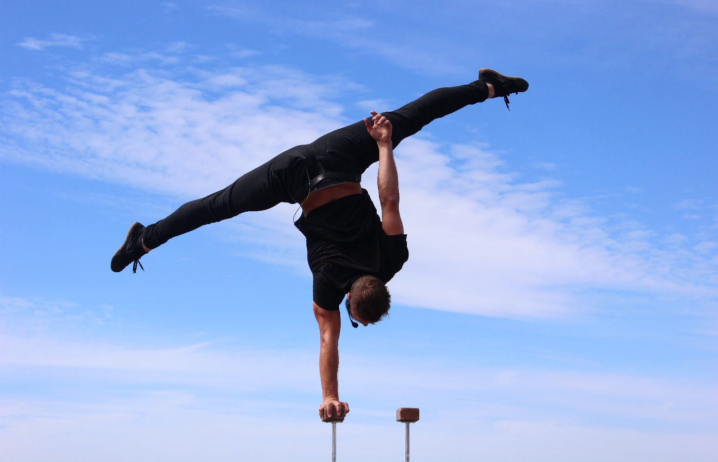 A man doing a one armed handstand on a small block