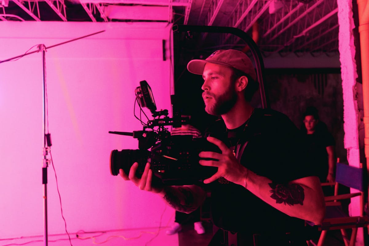 a guy in a baseball cap with a camers getting ready to shoot in studio