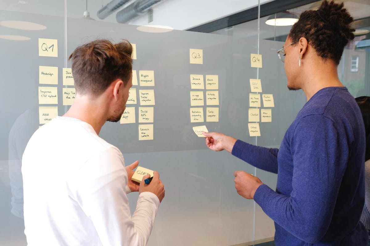 Two people planning a strategy with post its on a glass wall
