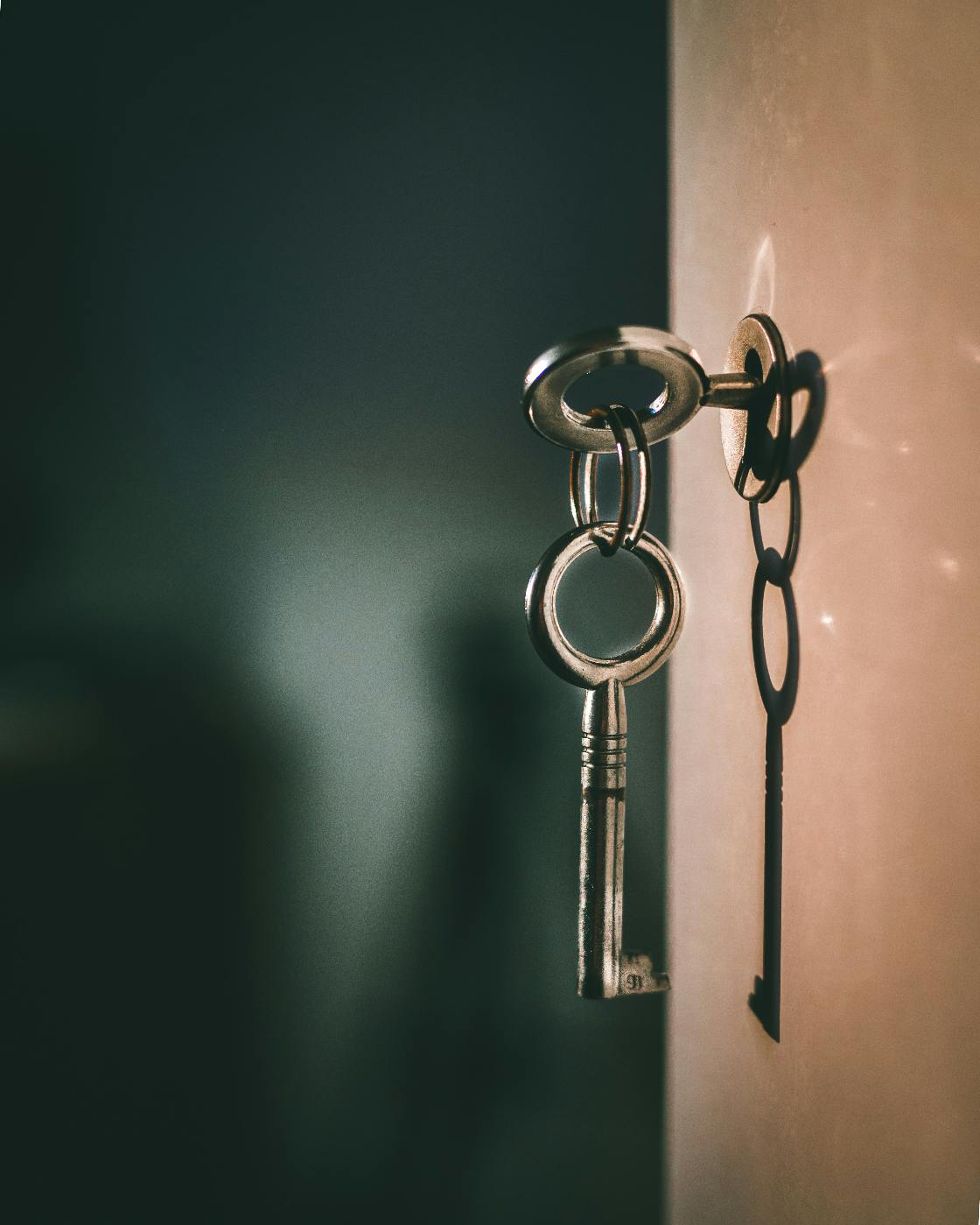 a skelteton key on a hook with its shadow on the wall