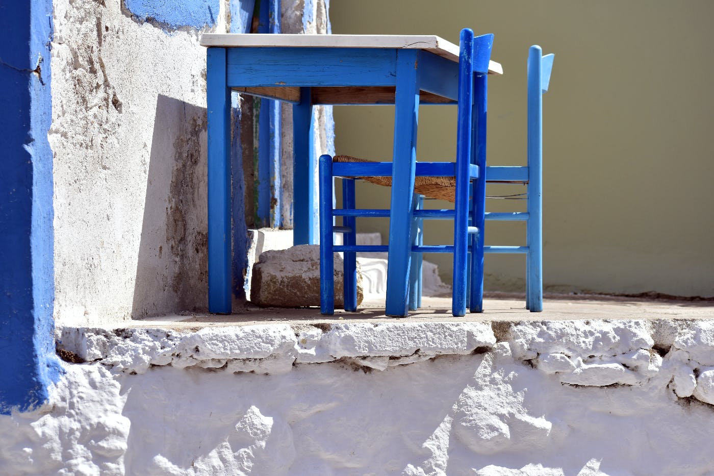 Blue desk with two blue chairs on a white patio