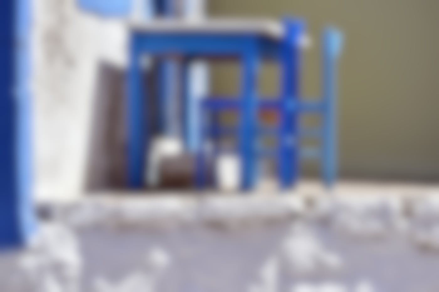 Blue desk with two blue chairs on a white patio