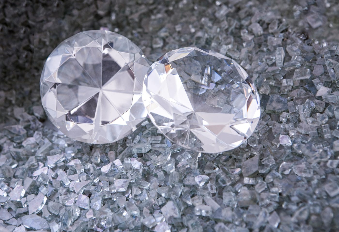 Two diamonds sitting on a pile of crushed glass