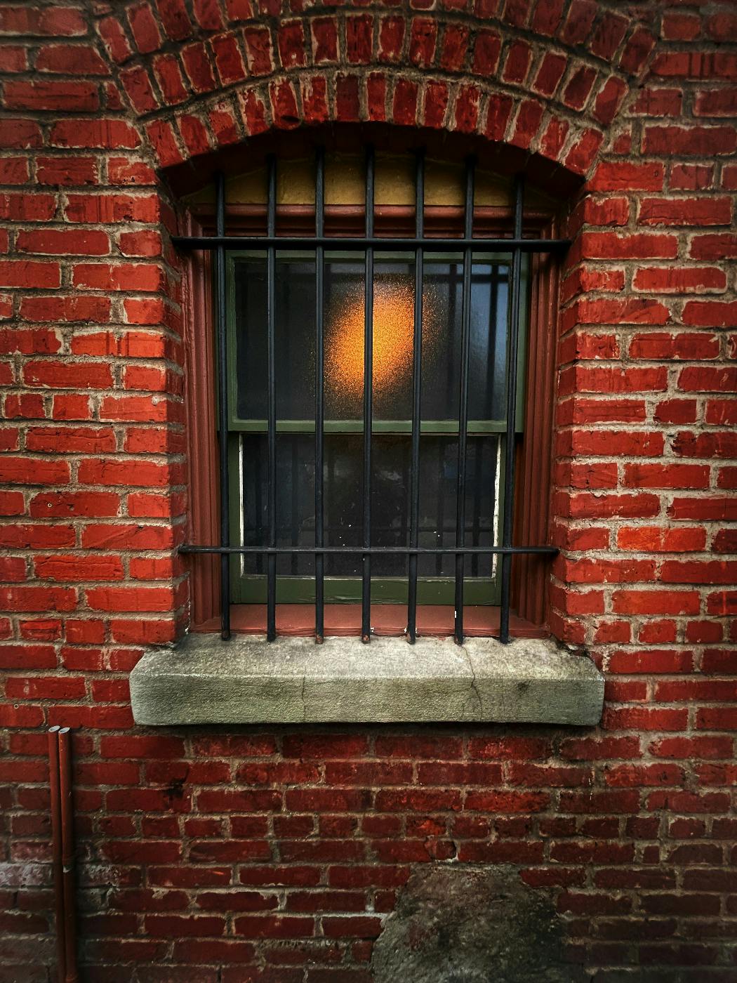 A window in a brick building with black bars on it