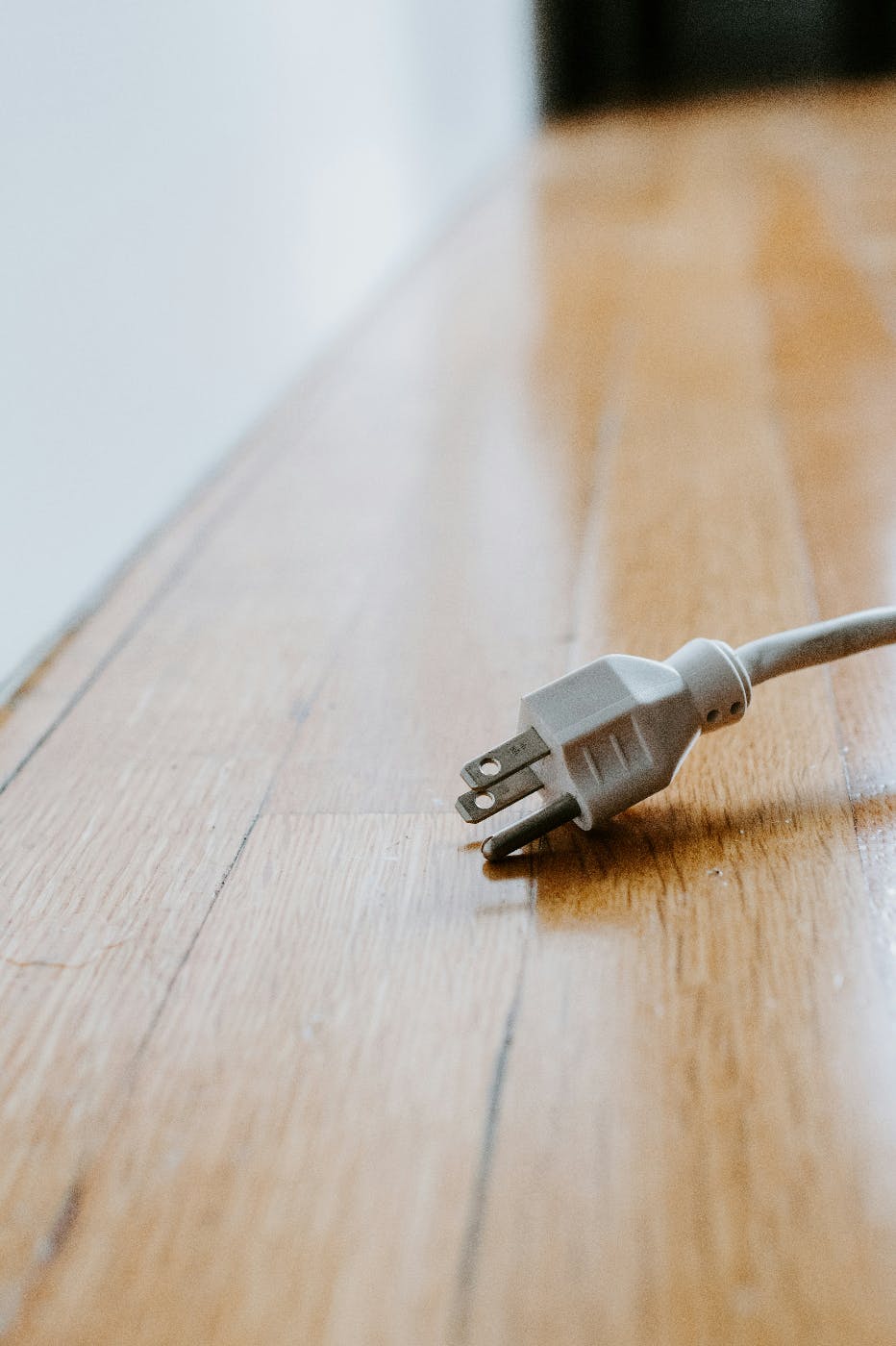 A three pronged plug sitting on a wood floor