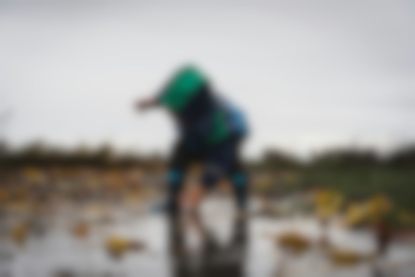 A child in rain gear playing in a puddle