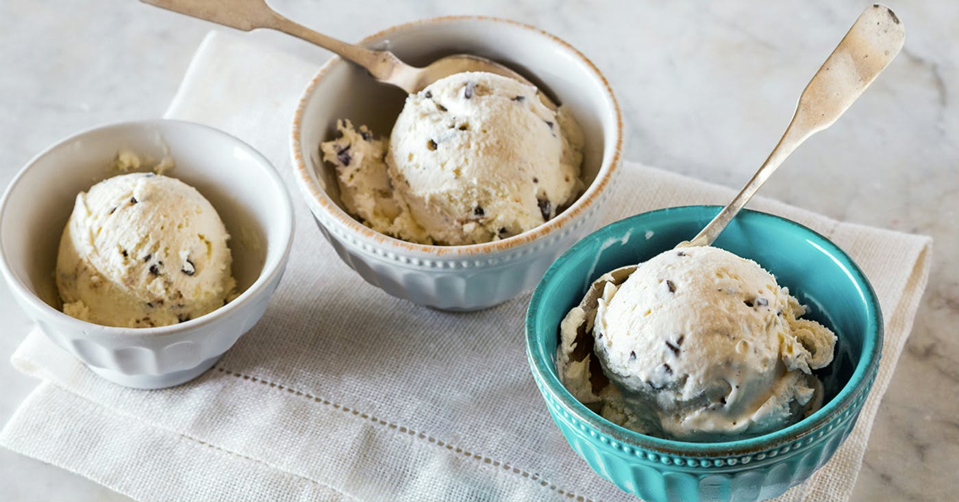 3 small bowls, 2 white, one blue all with a scoop of chocolate chip ice cream. The middle bowl and one on the right have spoon sin them