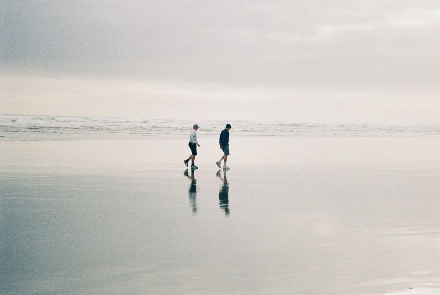 A couple on a beach walking on the wet sand of a receding tide